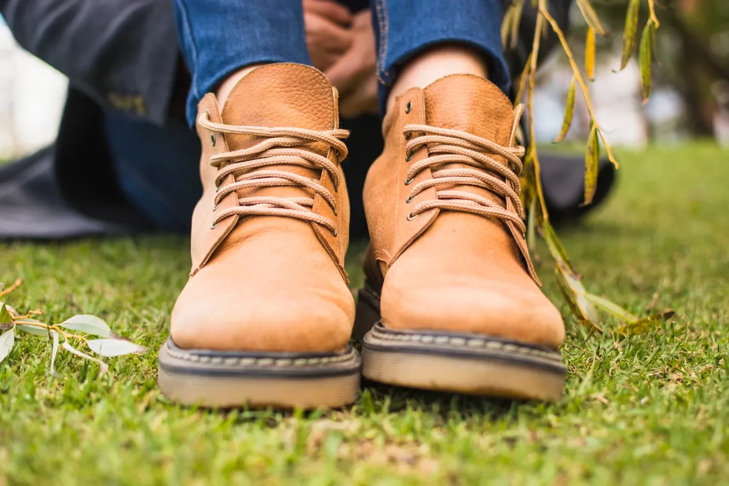 Botas de cuero marrón sobre césped, con cordones visibles, destacando un estilo casual y cómodo.